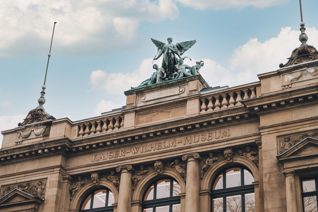 Das Kaiser Wilhelm Museum ziert die 1,7 Tonnen schwere Bronzegruppe Genius der Künste