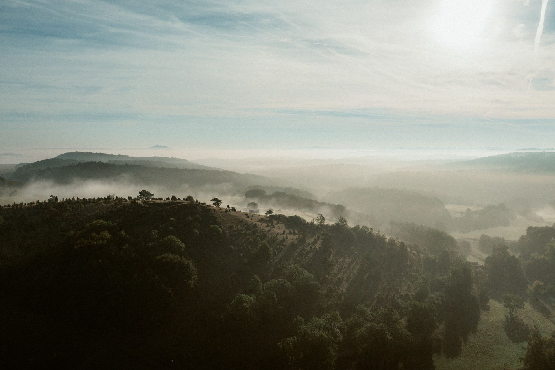 Frühnebel über bewaldeten Hügeln