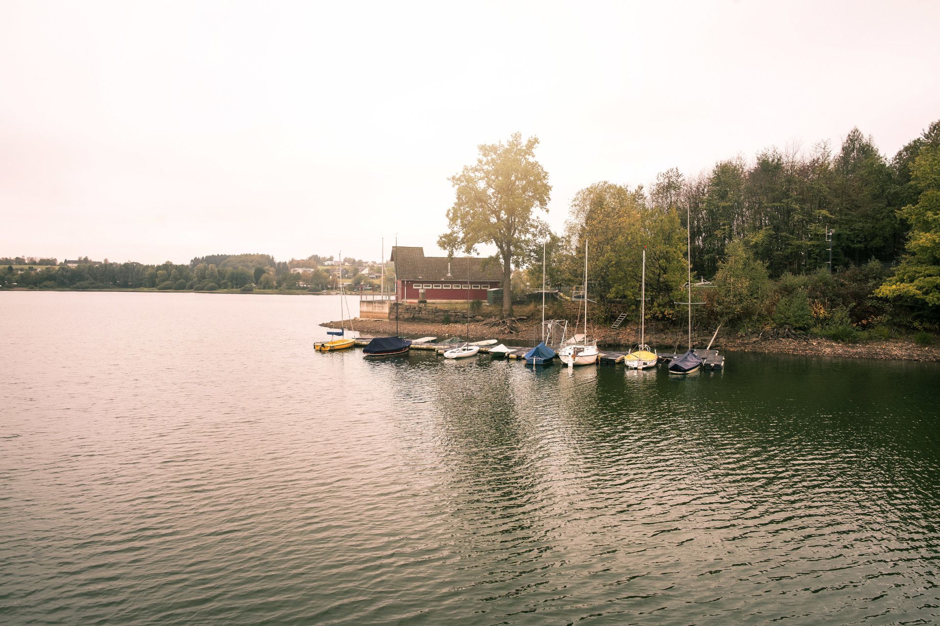 Segelboote liegen vor einem Holzhaus vor Anker