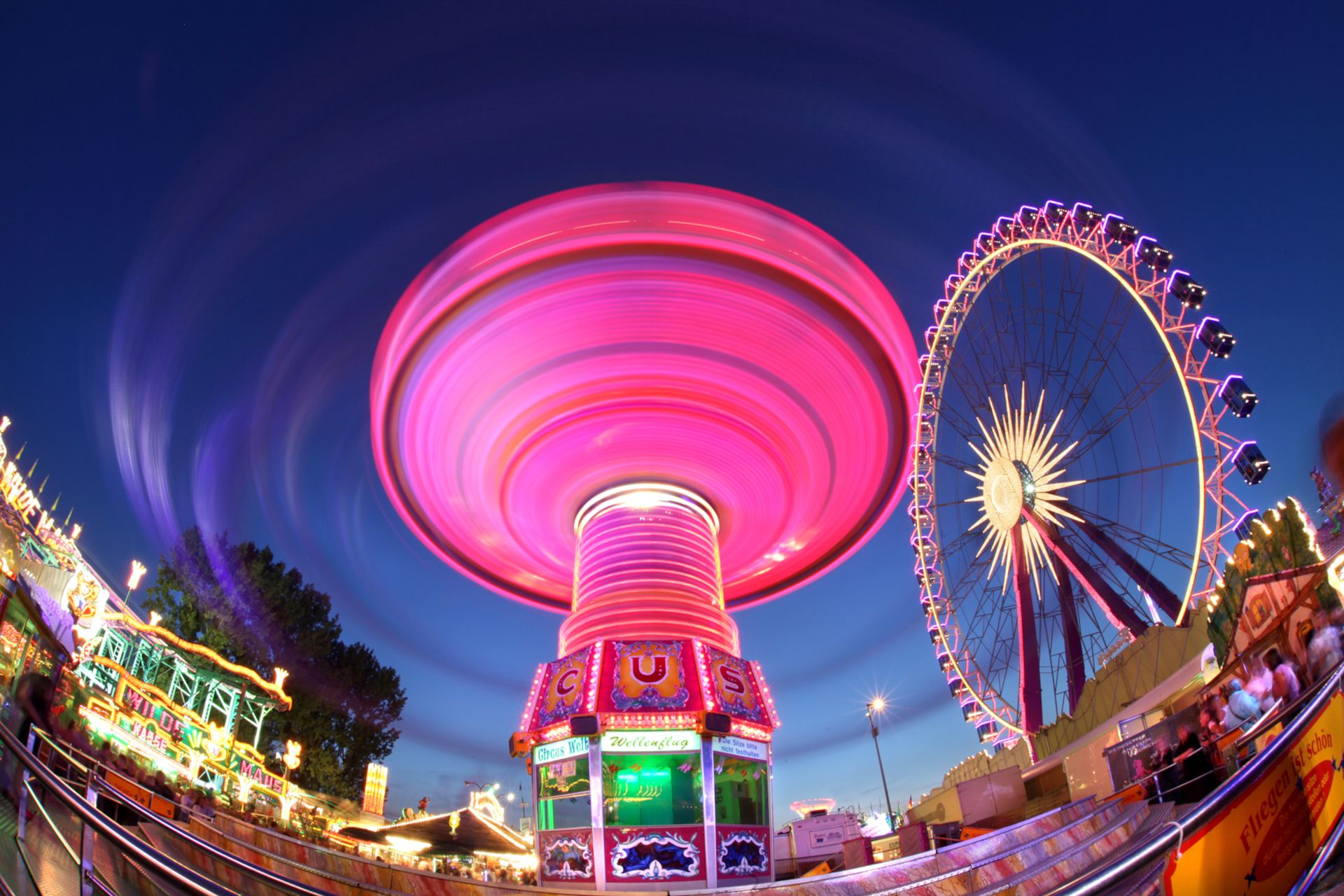 Das Kettenkarussell auf der Cranger Kirmes leuchtet in der Dunkelheit in hellen Farben, während es seine Runden dreht