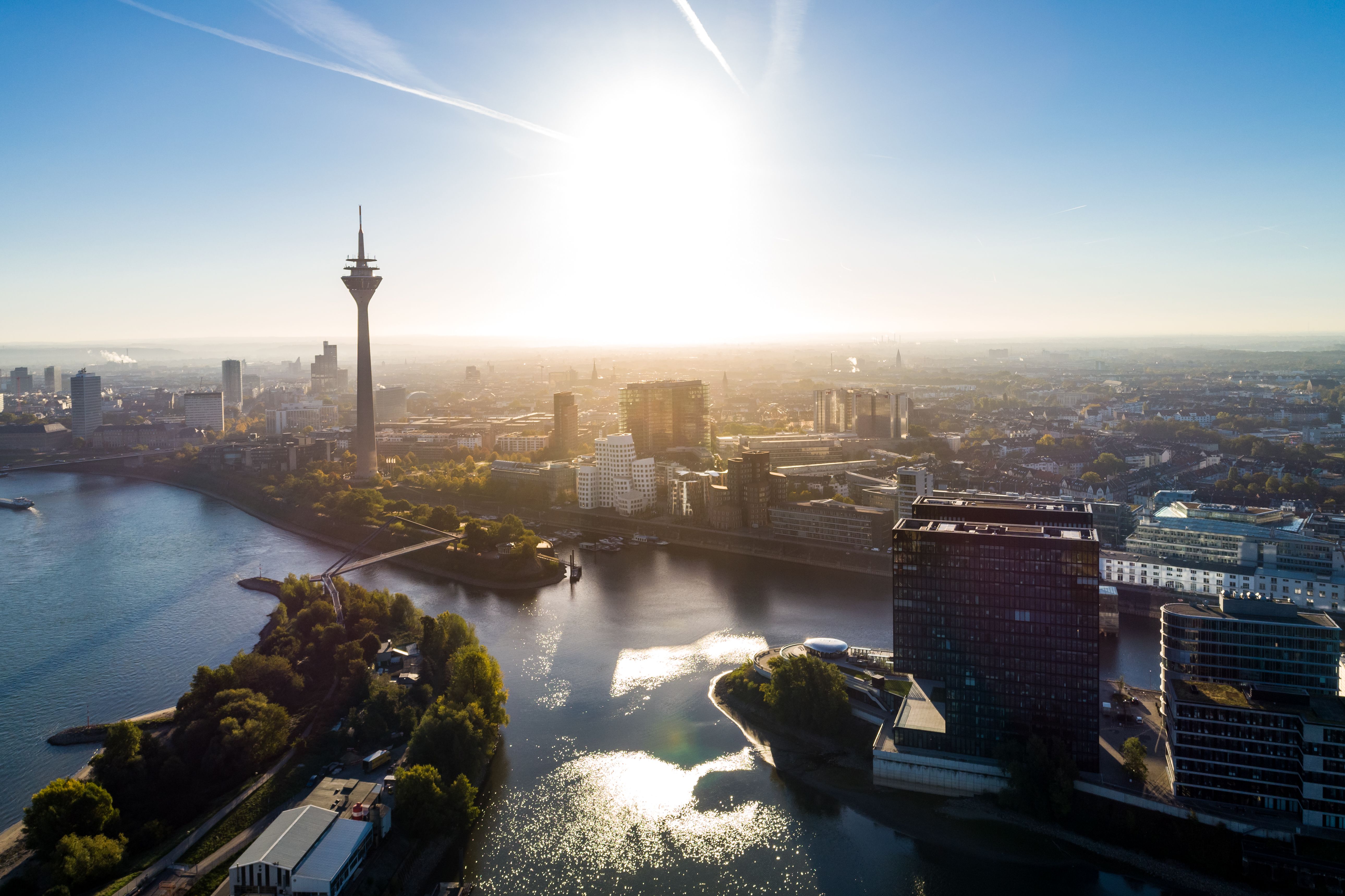 Sonne über der Stadt, im Vordergrund Rhein, Hafenbecken und Fernsehturm