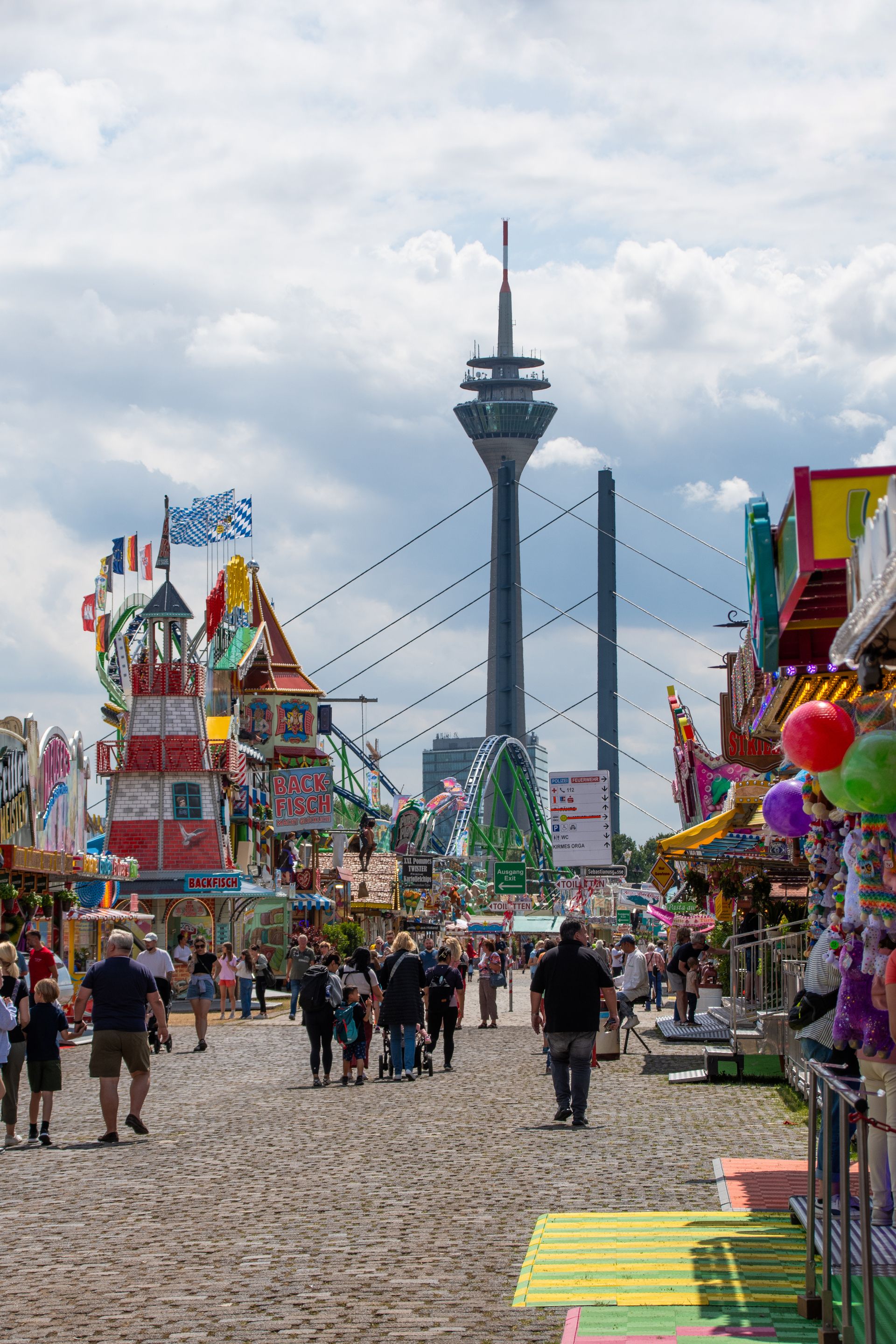 Der Düsseldorfer Fernsehturm ragt zwischen den Fahrgeschäften und Essensständen der Rheinkirmes empor