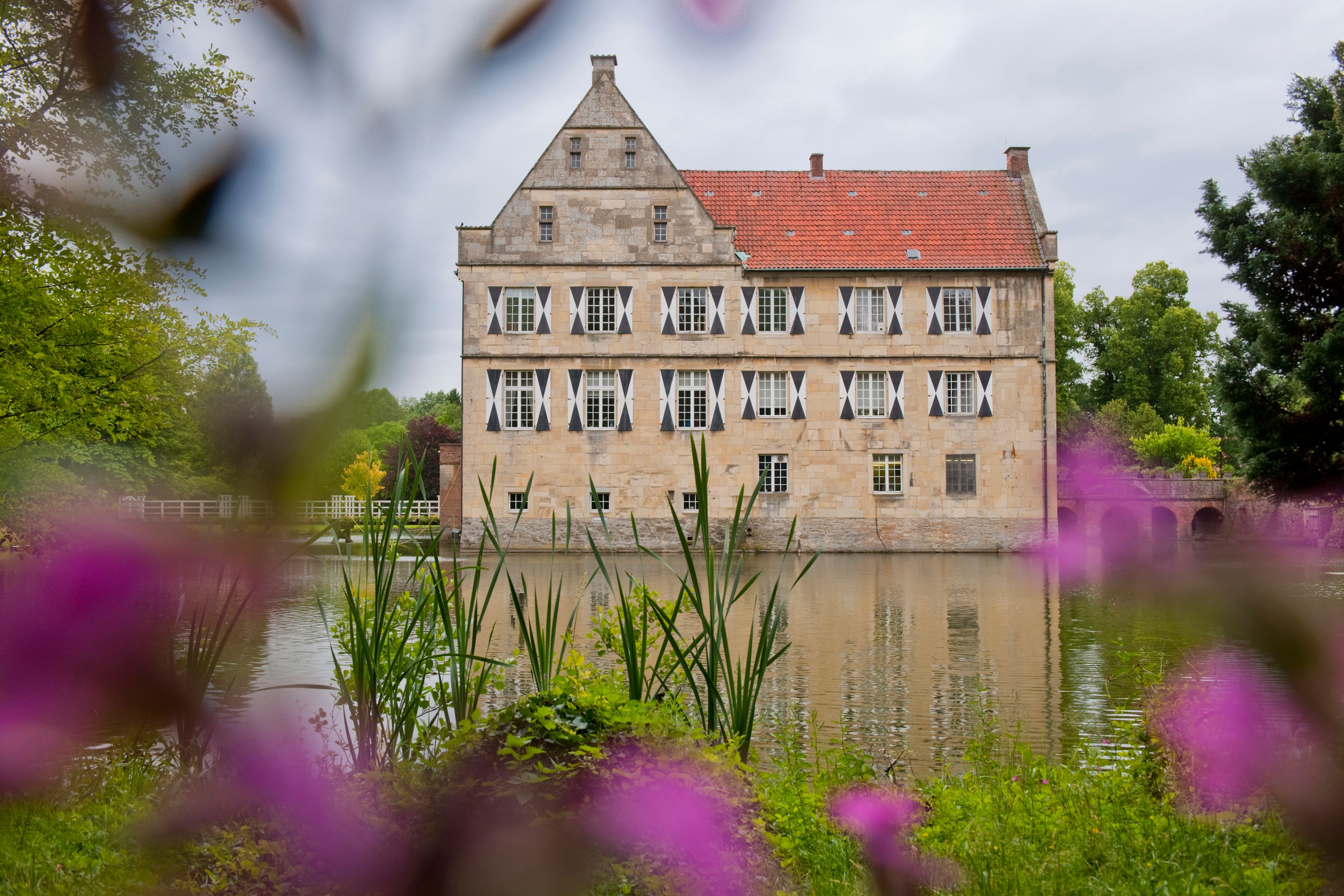 Oliver Franke, Tourismus NRW e.V., Die Fassade der Burg Hülshof mit Wasser und Blumen in Havixbeck