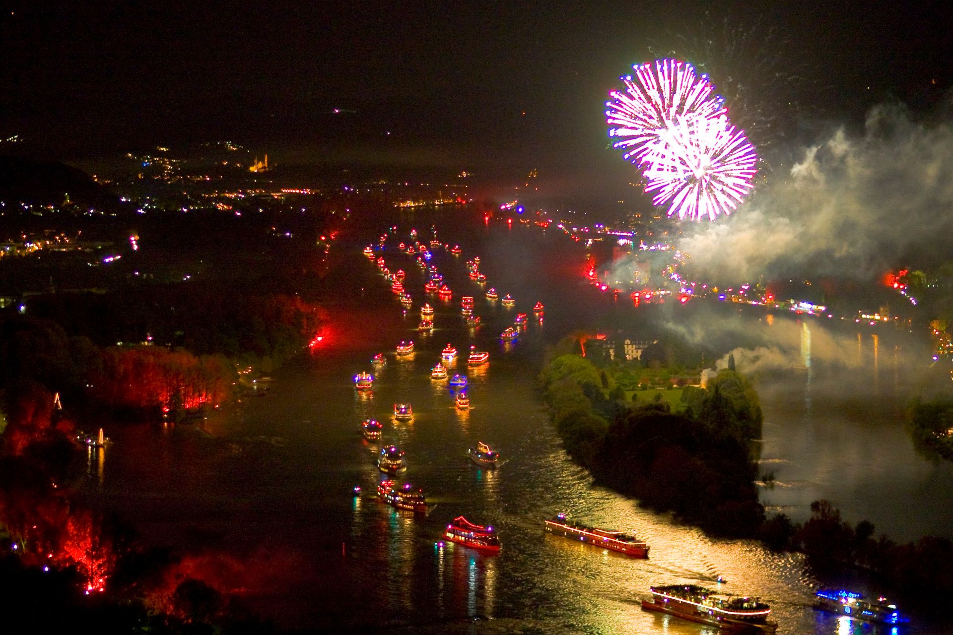 Eine Schiffskolonne zieht über den Rhein. Die Schiffe leuchten in hellen Farben